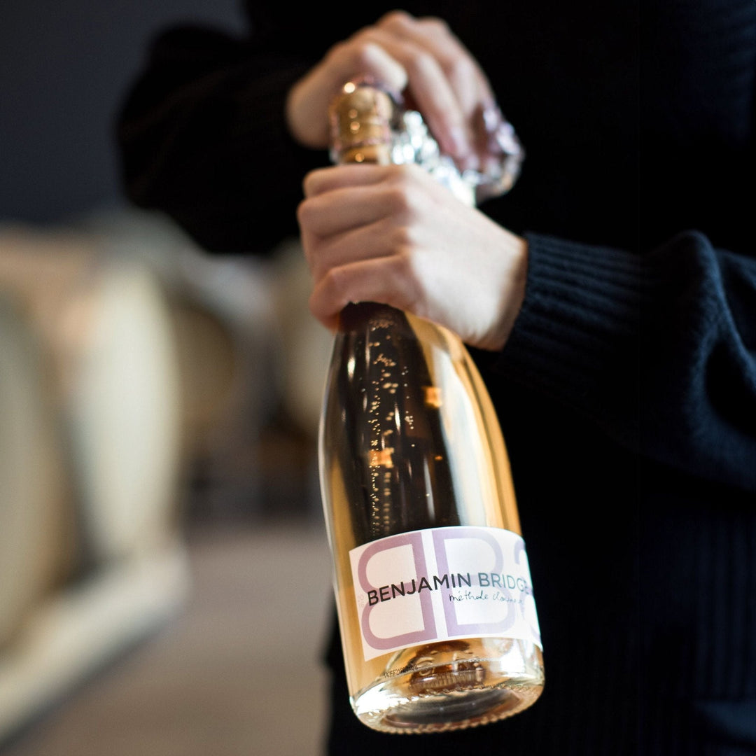 Benjamin Bridge sparkling wine being opened, showcasing a méthode classique rosé bottle in an elegant winery setting.