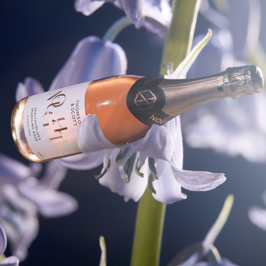 Noughty Sparkling Rosé bottle displayed gracefully amidst soft lavender flowers, highlighting its delicate and elegant essence.