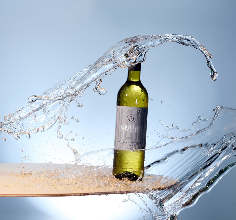 A dynamic image of Noughty White Dealcoholized Wine, captured mid-splash with water in the background, emphasizing freshness and vibrancy.