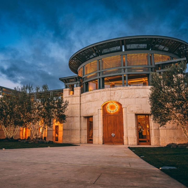 The illuminated facade of Opus One Winery at night, with its signature round design and welcoming lights.