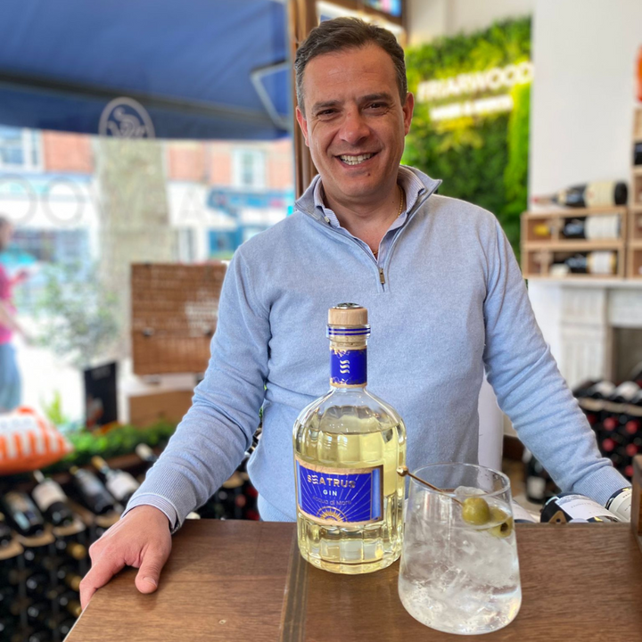 Guilio Amodio, co-founder of Seatrus Gin, showcasing the Seatrus Gin bottle alongside a gin cocktail at a tasting event.