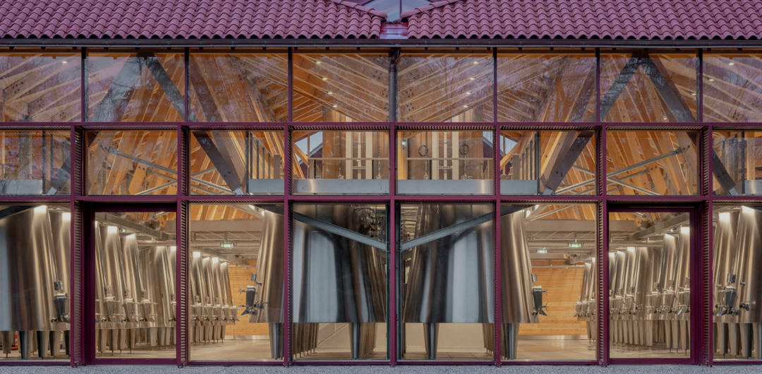 A modern winery facility at Château Cantenac Brown featuring gleaming stainless steel fermentation tanks and glass walls showcasing the interior structure.