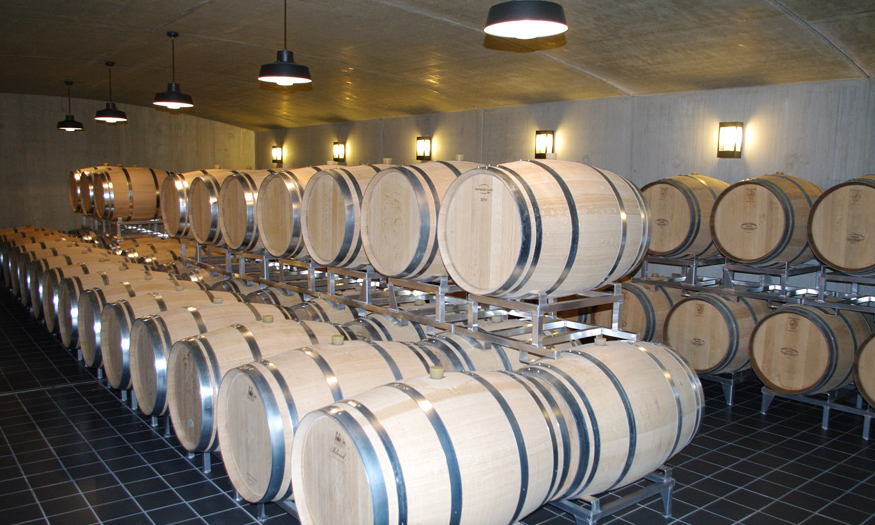 Wine barrels in a dimly lit cellar, emphasizing traditional aging methods.