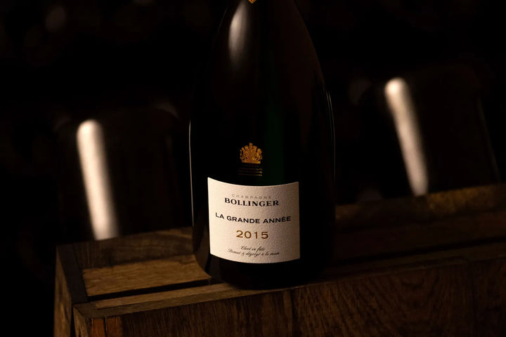 Bollinger La Grande Année 2015 Champagne bottle in a dimly lit cellar, showcasing premium winemaking.