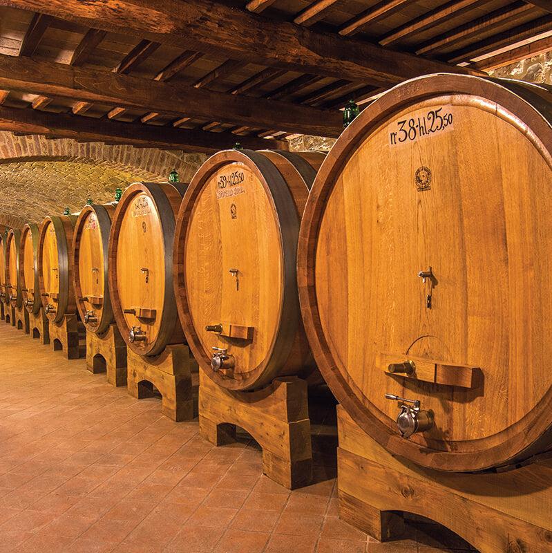 Traditional wine cellar at Capanna with large wooden barrels neatly arranged under rustic wooden beams.