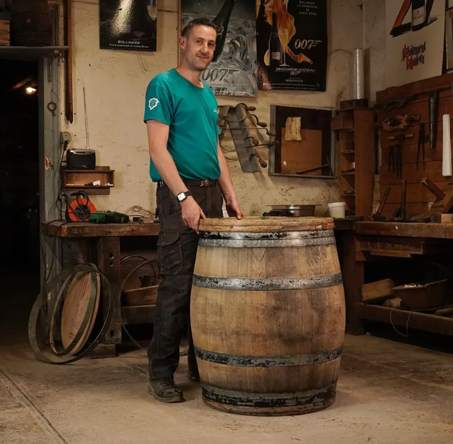 Bollinger cooper working on a traditional oak barrel in the workshop, preserving the craftsmanship of winemaking.