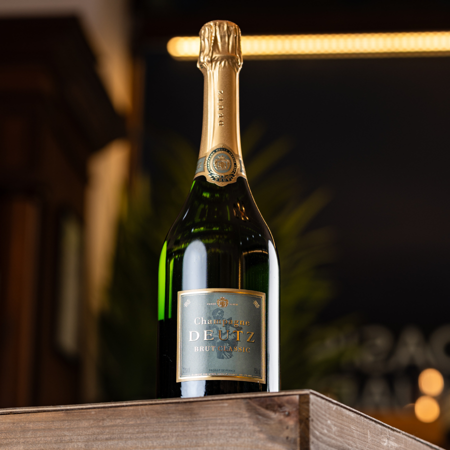 A bottle of Deutz Brut Classic Champagne on a wooden crate.