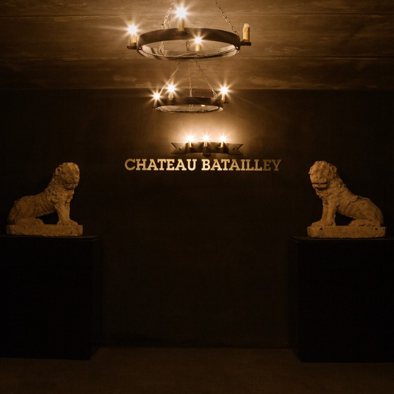 Illuminated entrance to Chateau Batailley’s wine cellar, flanked by lion statues, creating a grand and inviting ambiance.