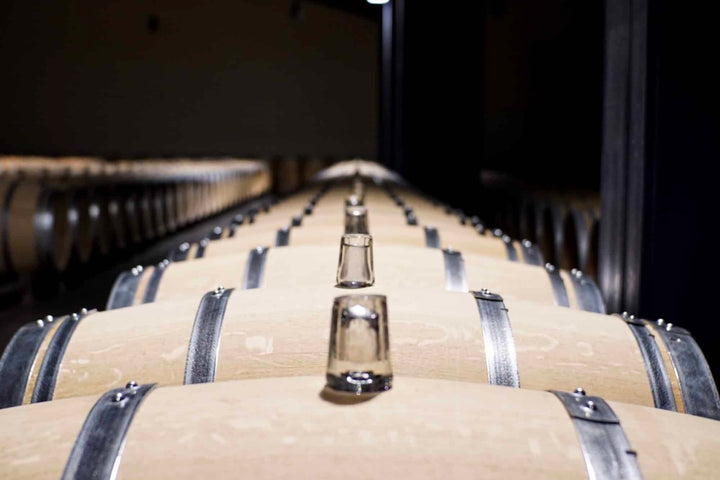 Château Dauzac wine cellar with rows of aging barrels.