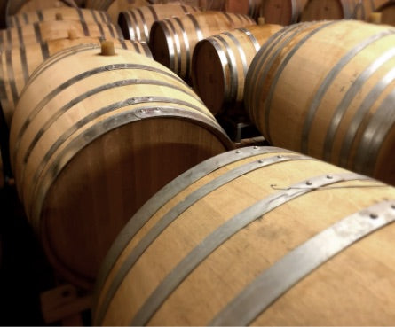 Wine barrels aging premium Bordeaux wines at Château des Landes winery.