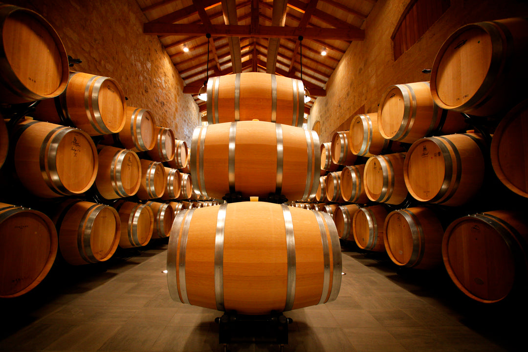 Château Fonplegade wine barrels in the aging cellar, showcasing traditional oak cask storage.