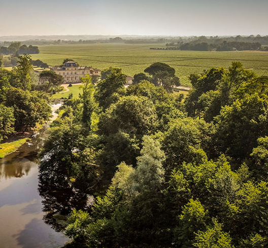 A stunning aerial view of Château Giscours estate, a historic Bordeaux wine producer in the Margaux appellation. Surrounded by lush vineyards and picturesque landscapes, the château embodies the elegance and tradition behind its renowned Cru Classé wines.