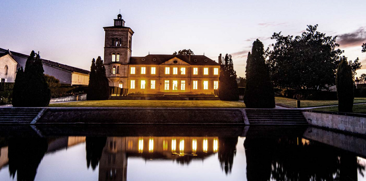 Chateau Lagrange illuminated at night with its reflection in the water.