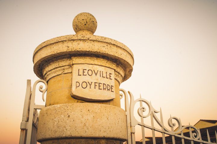 The entrance gate of Château Léoville-Poyferré with stone pillars and vineyard surroundings.