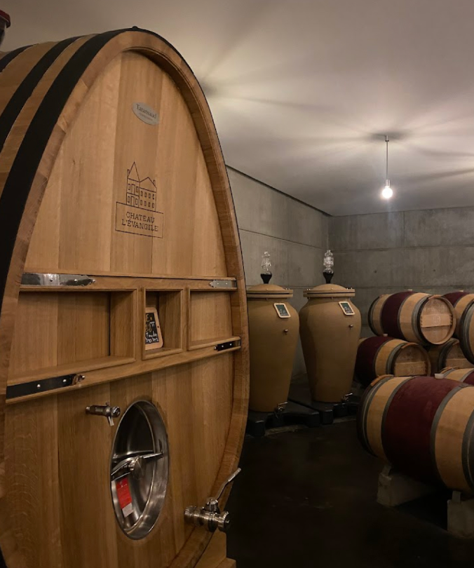 Oak barrels and clay amphorae aging wine at Château L'Évangile’s modern cellar.