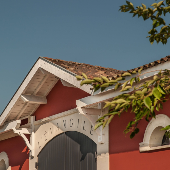 Exterior view of Château L'Évangile’s red building, symbolizing its iconic vineyard entrance.