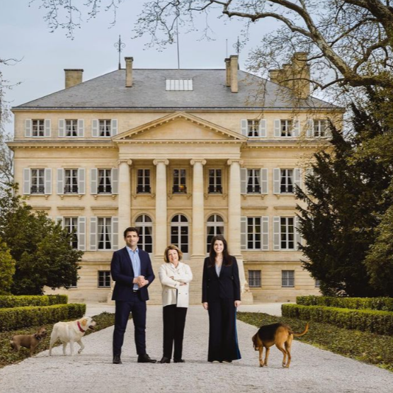 The family behind Château Margaux, standing in front of the historic estate with their dogs.