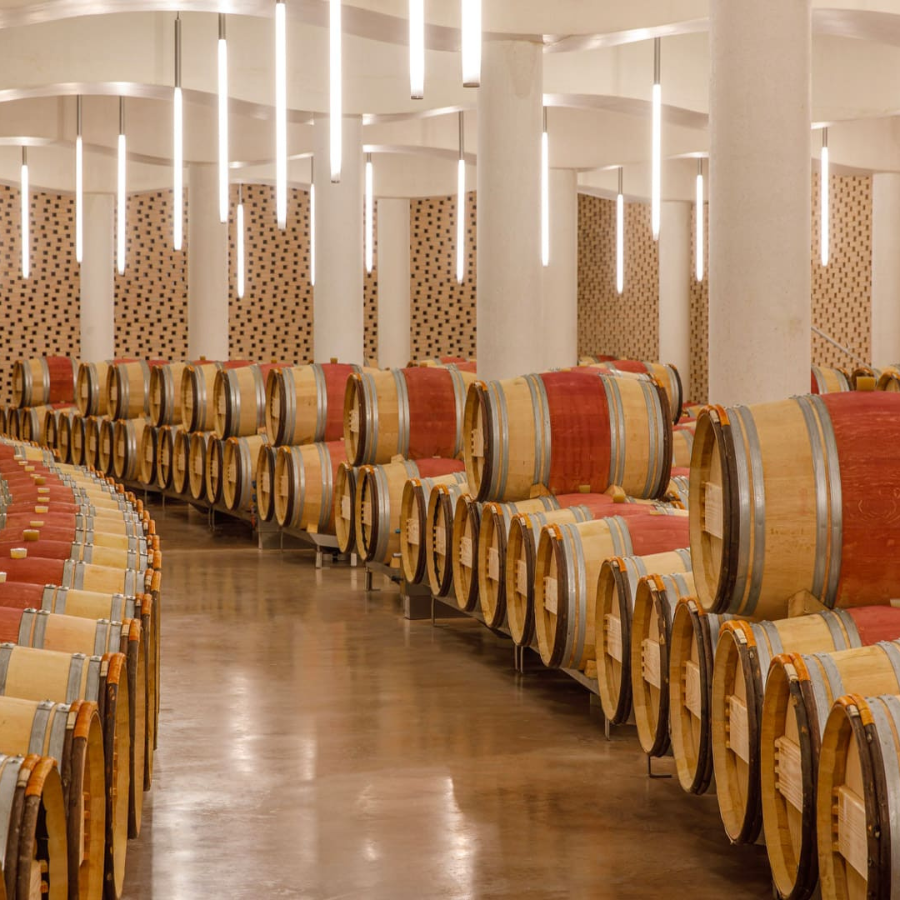 Château Cheval Blanc cellar showcasing rows of oak barrels, highlighting their meticulous ageing process for fine wines.