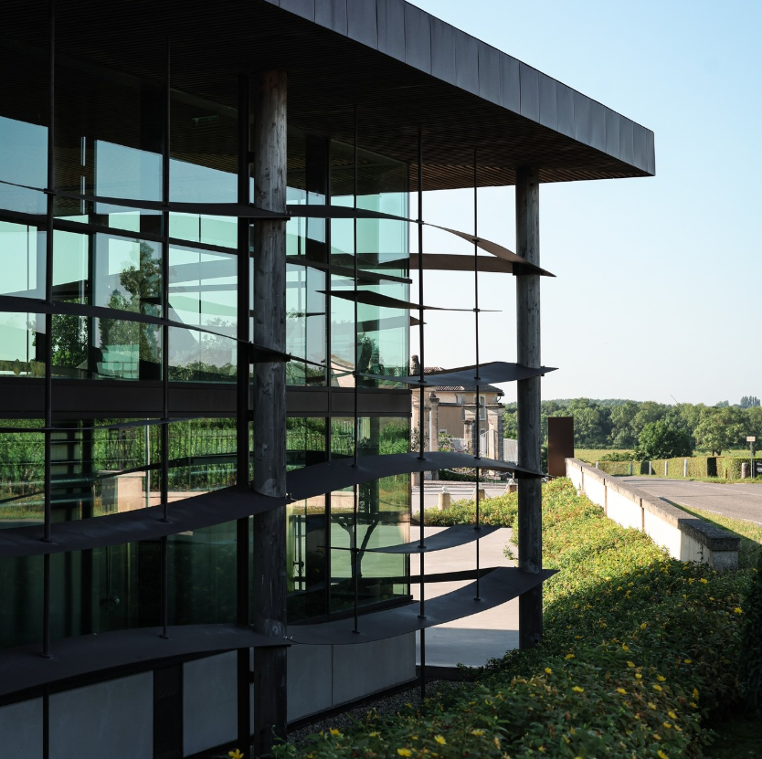 Exterior view of a contemporary winery with a glass facade and surrounding vineyards.