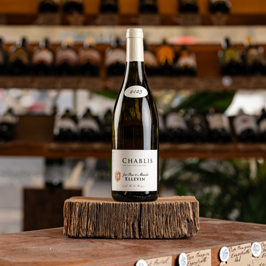 A bottle of Domaine Ellevin Chablis 2023 on a wooden display.