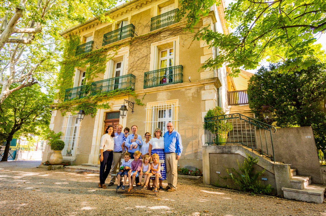 Family of Domaine La Croix Belle standing in front of the historic estate building in Languedoc, surrounded by lush greenery