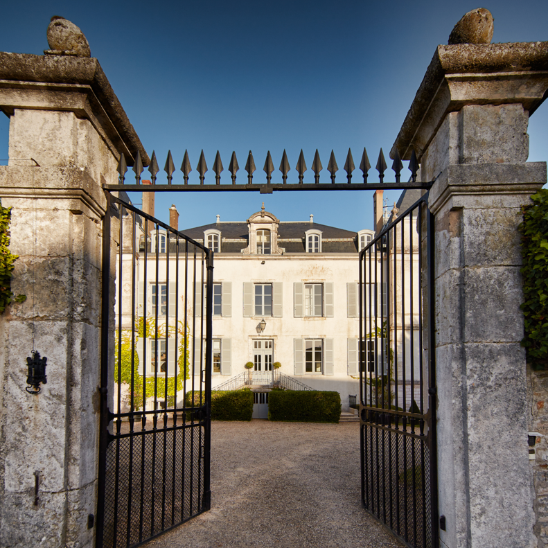 A photo of the gates opening to domaine devillard with the chateau in the background