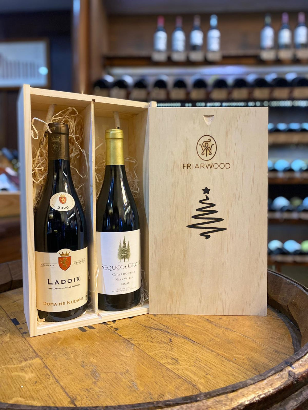 Luxury Friarwood wooden gift box containing a bottle of Domaine Nudant Ladoix 2020 and Sequoia Grove Chardonnay 2020, displayed in a wine shop