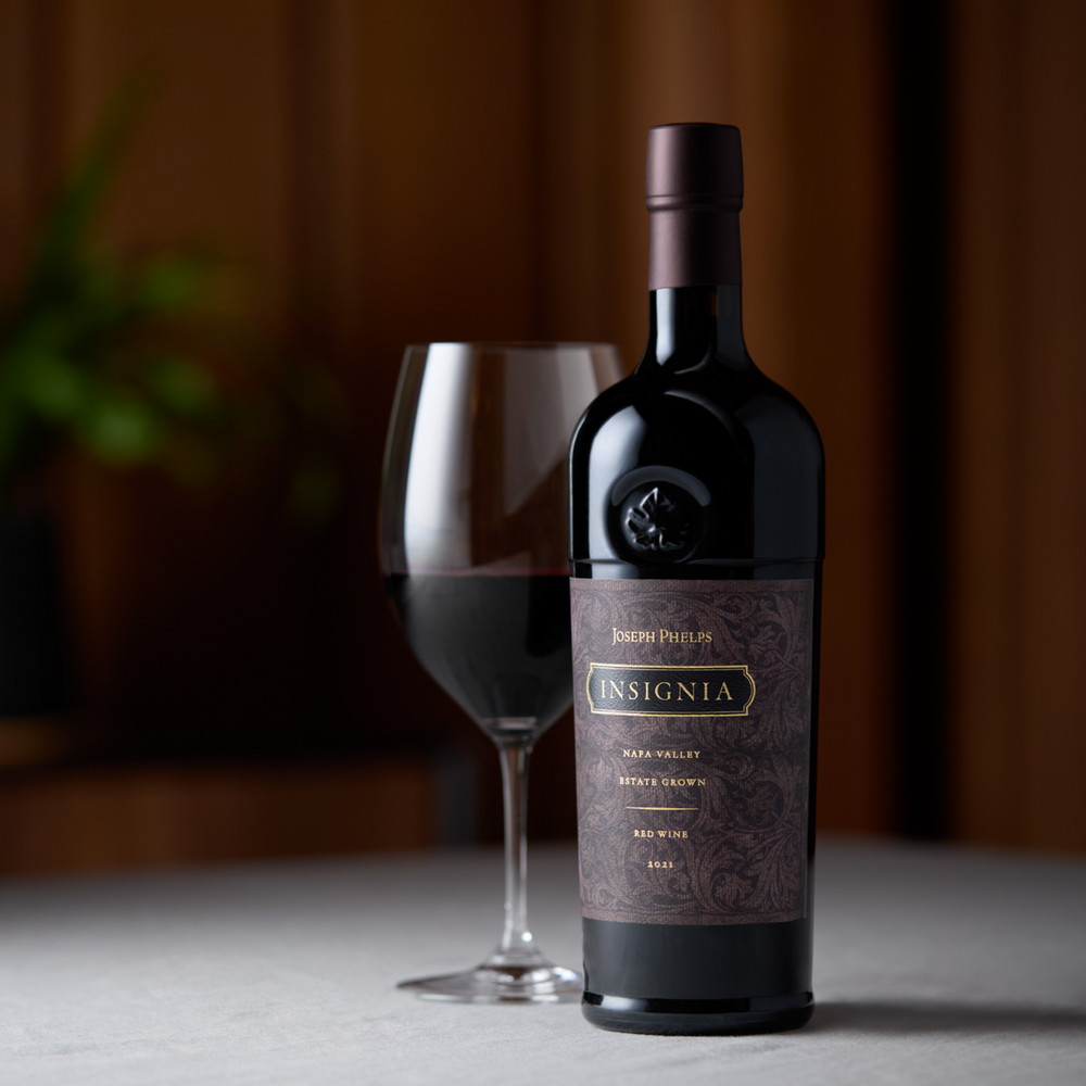 Joseph Phelps Insignia 2021 bottle served with a glass of red wine, highlighting its premium Napa Valley craftsmanship.