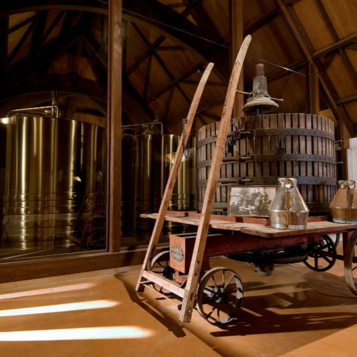 Traditional wine production room at Domaine de Ladoucette, showcasing historical winemaking tools, wooden press, and modern fermentation tanks.