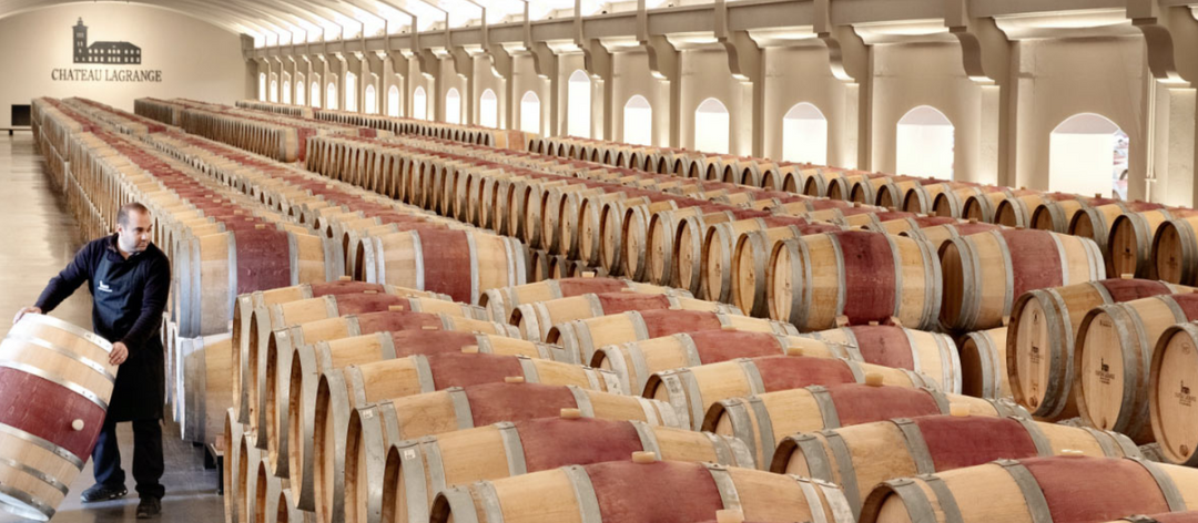 Chateau Lagrange barrel room filled with rows of oak barrels for wine aging.