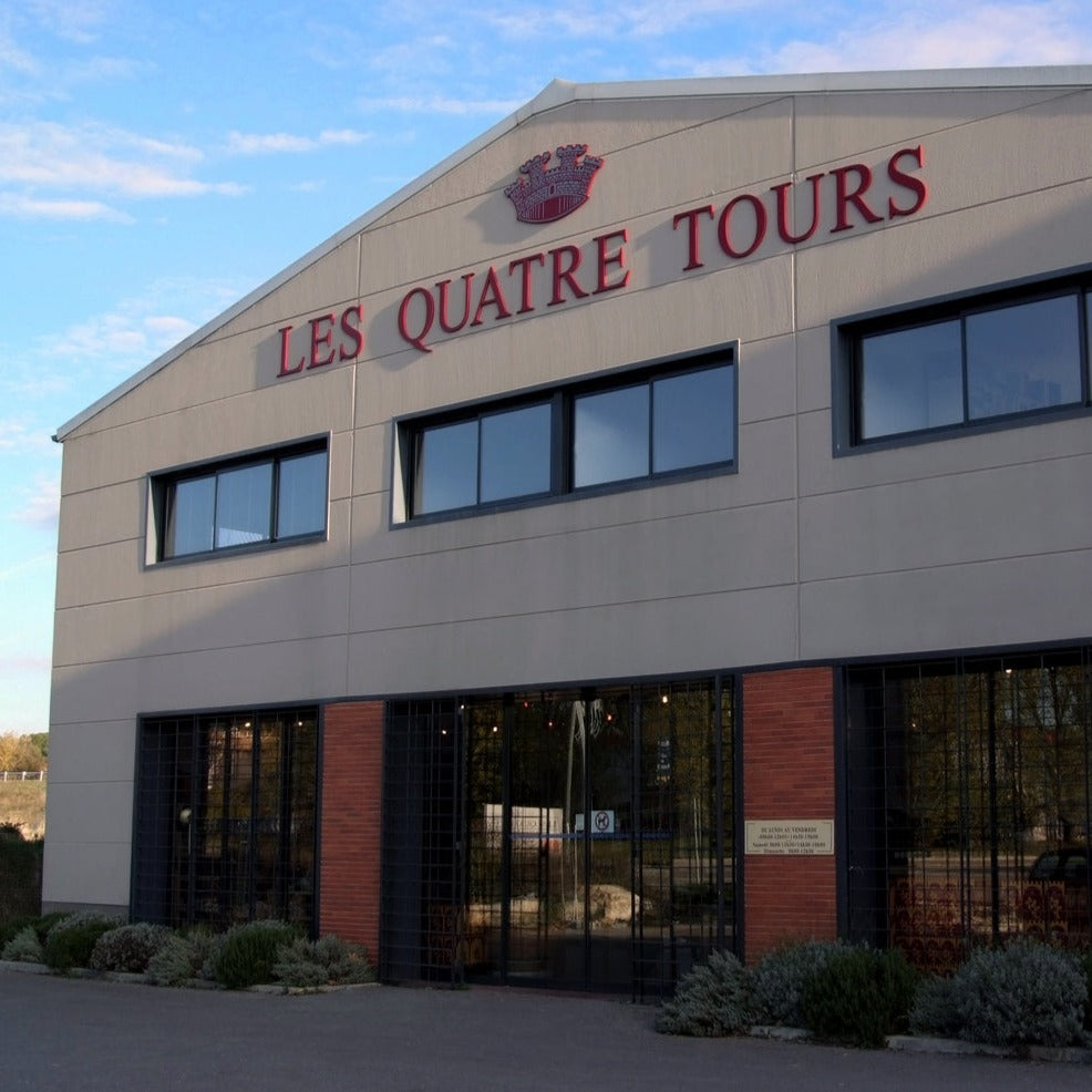 The Les Quatre Tours winery building with its iconic red signage and modern architecture.