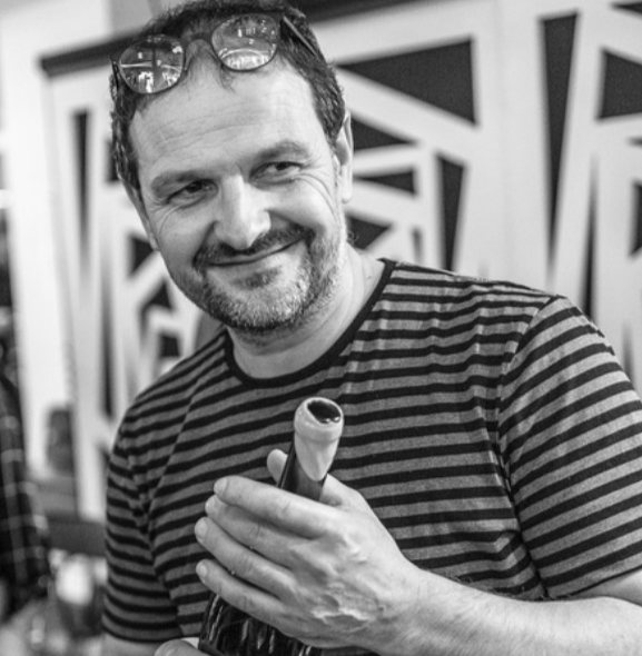 Loic Mahe holding a wine bottle and smiling during a wine tasting event.