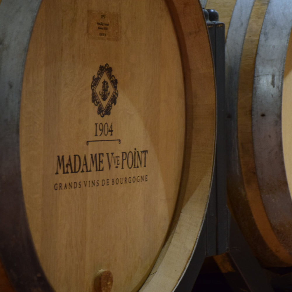 A close-up of a wooden wine barrel with the "Madame Veuve Point" label and the year "1904" inscribed on it.