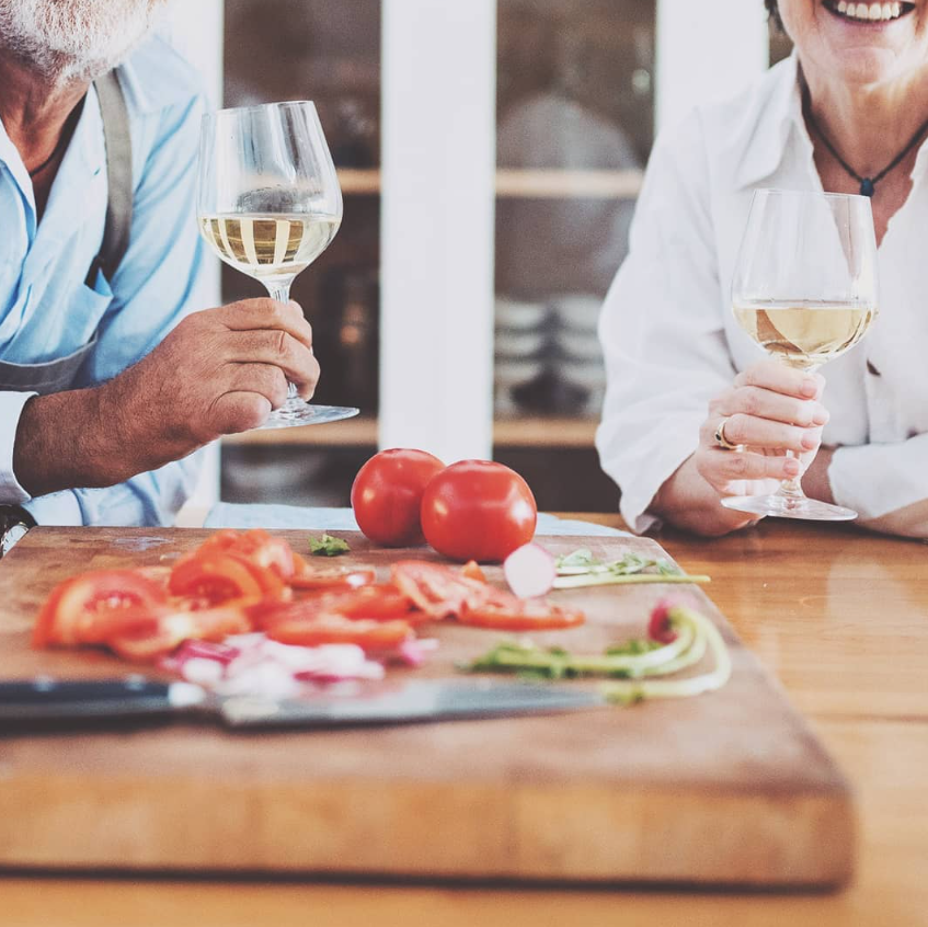 A close-up of two people enjoying white wine alongside fresh ingredients at Marques winery.