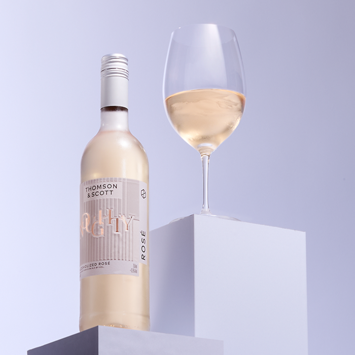 Noughty Rosé non-alcoholic wine bottle by Thomson & Scott with a glass of rosé wine on display.