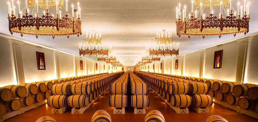 An elegant barrel-aging room at Château Pape Clément, illuminated by grand chandeliers.