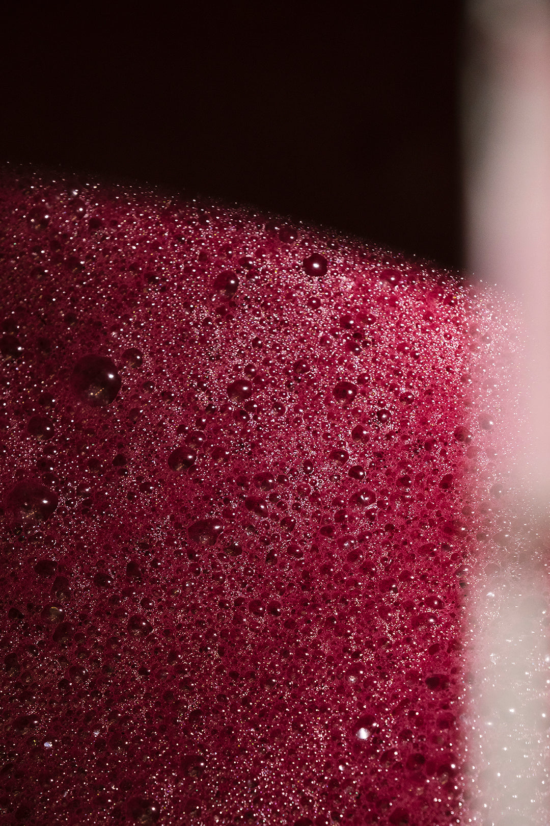 Close-up of red wine bubbles forming during the fermentation process.