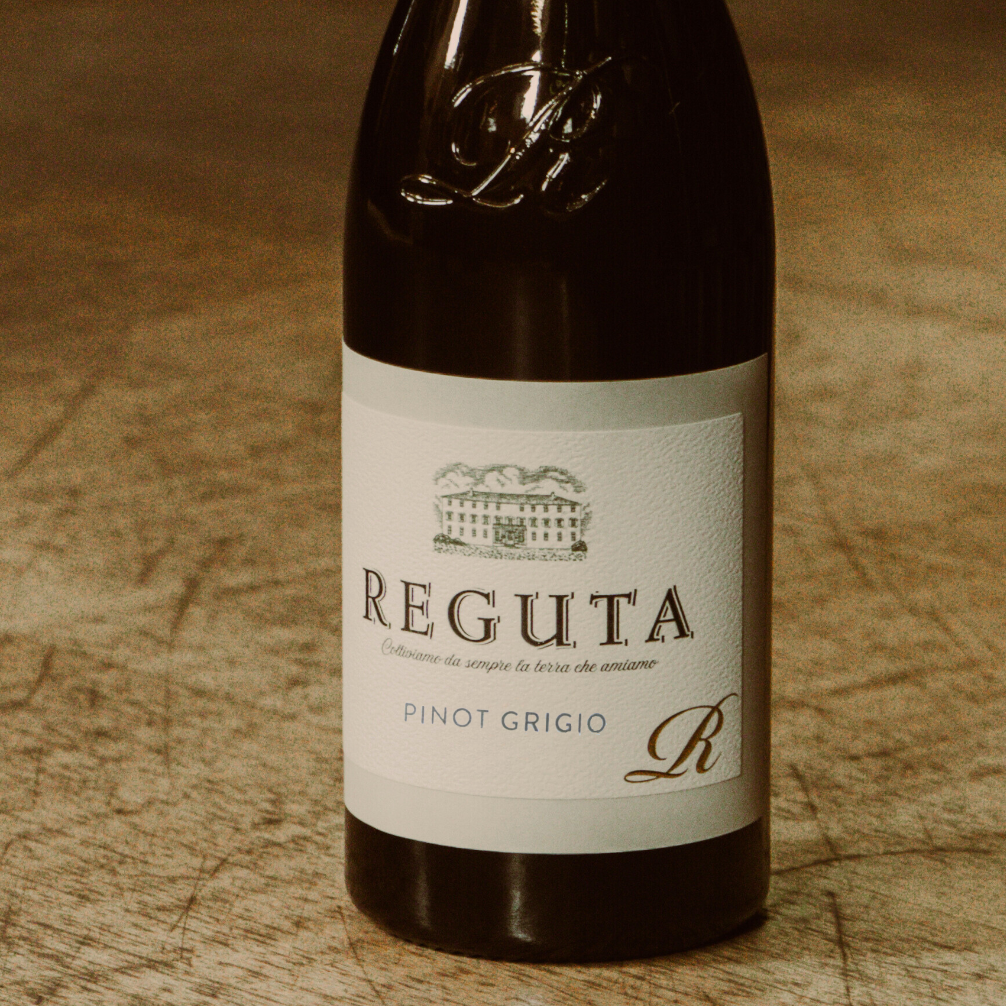 Reguta Pinot Grigio wine bottle, featuring a minimalist label design with an illustration of the estate, representing this Italian white wine known for its fresh and crisp characteristics