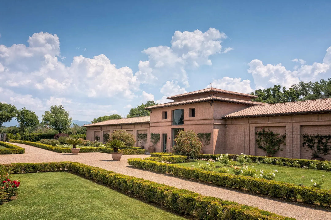 The stunning estate of Sassicaia winery in Tuscany, surrounded by lush vineyards under a bright blue sky.