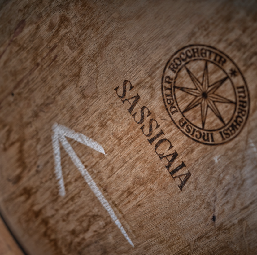 A close-up of a wooden wine barrel stamped with the Sassicaia logo, showcasing the craftsmanship of winemaking.