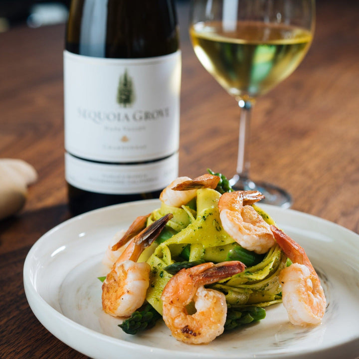 Sequoia Grove Chardonnay paired with a plate of shrimp pasta, elegantly served on a wooden table setting.