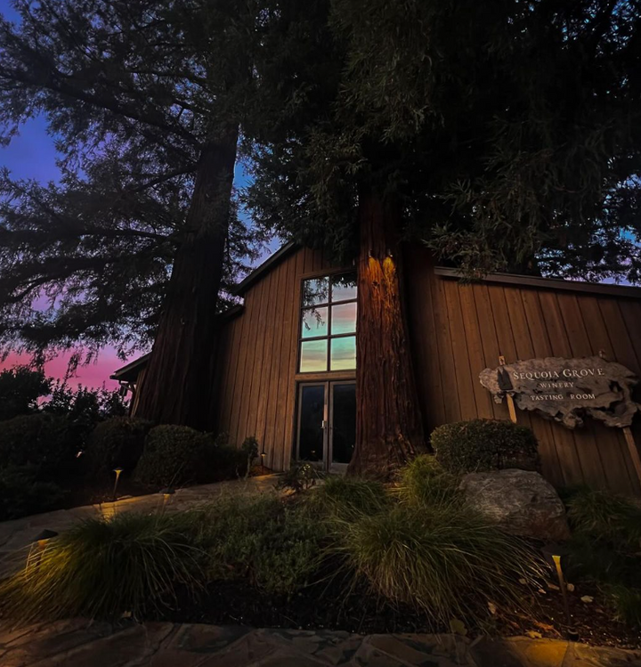 Exterior of Sequoia Grove Winery tasting room with redwood trees at dusk.