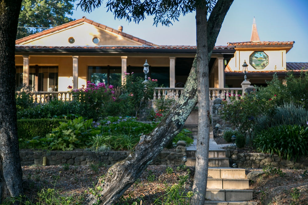 The Trinité Estate winery house in Sonoma County, surrounded by lush gardens and vineyards, showcasing a beautiful blend of nature and architecture.