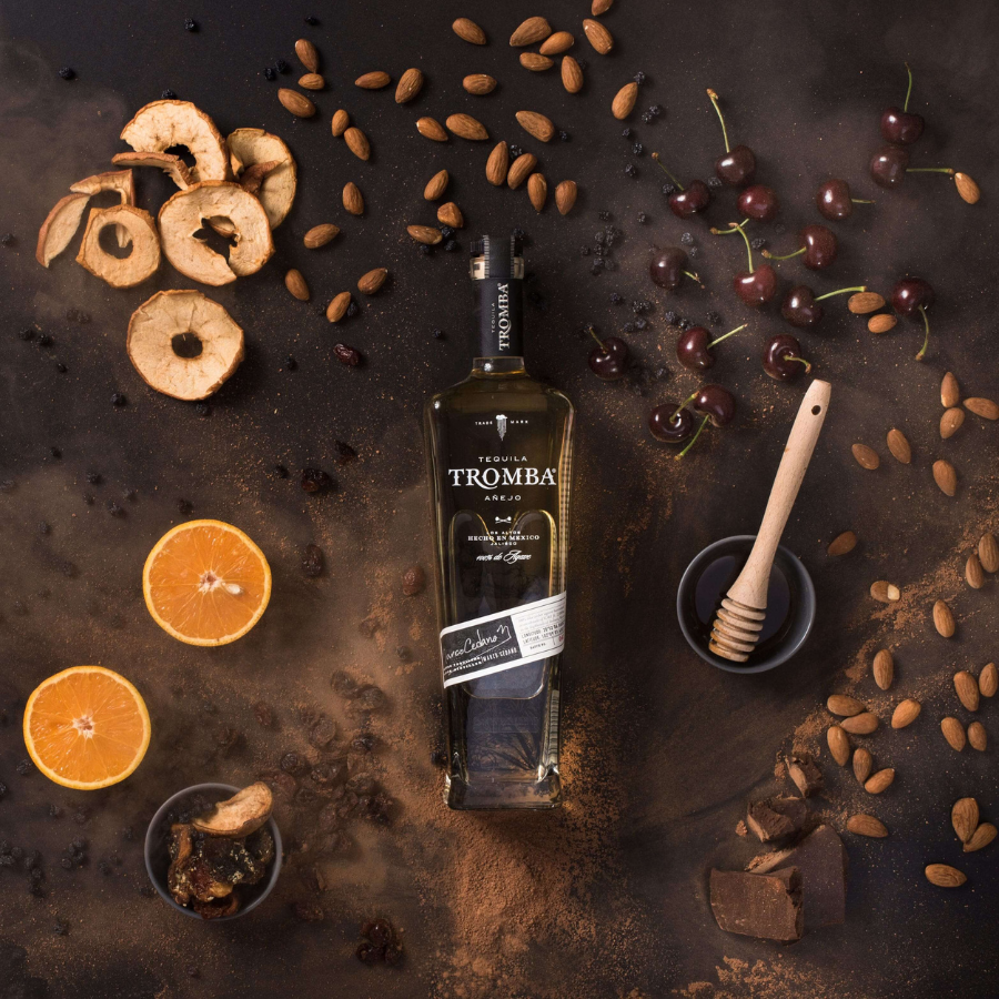 Tromba Añejo Tequila surrounded by dried fruits, honey, almonds, cherries, and rich cocoa powder.