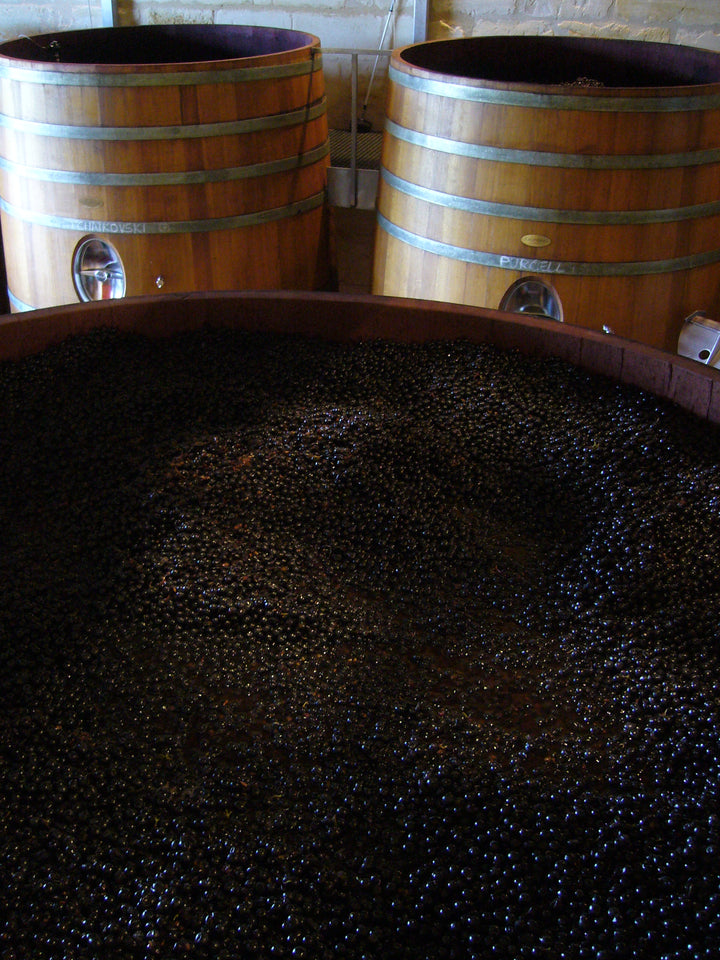 Traditional wine fermentation process in wooden vats at a Bordeaux winery.