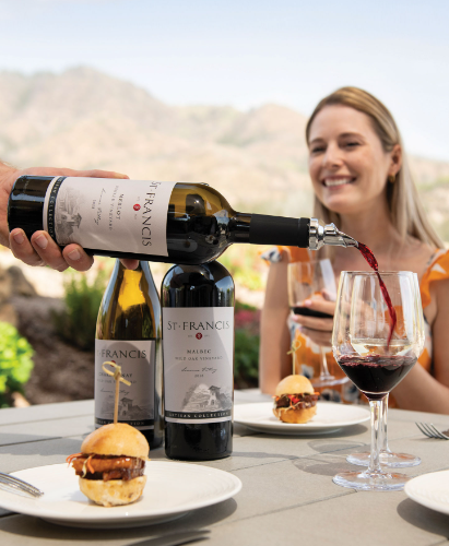 A bottle of St. Francis wine being poured into a glass alongside gourmet food pairings.