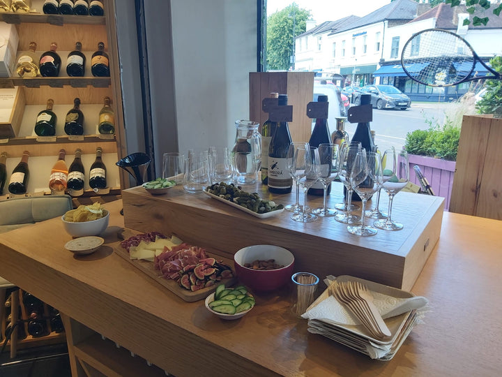 A beautifully set wine tasting event at Friarwood, featuring an elegant spread of cheeses, charcuterie, fresh figs, and wine bottles with glasses ready for sampling.