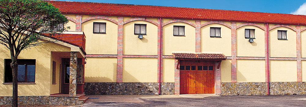 Exterior view of the winery facade with rustic brick and stone architecture under a red-tiled roof.